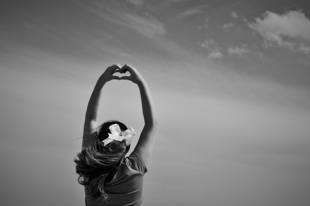 Girl holding hands in a heart shape above head