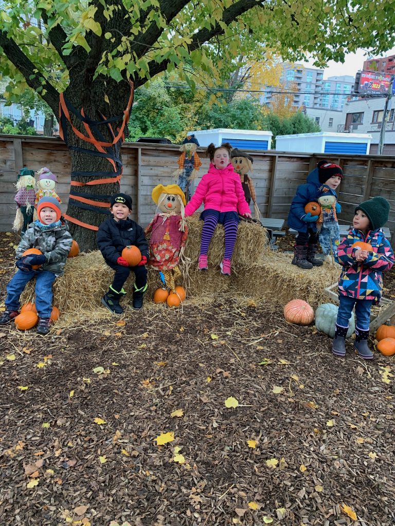 Students smiling in backyard with pumpkins