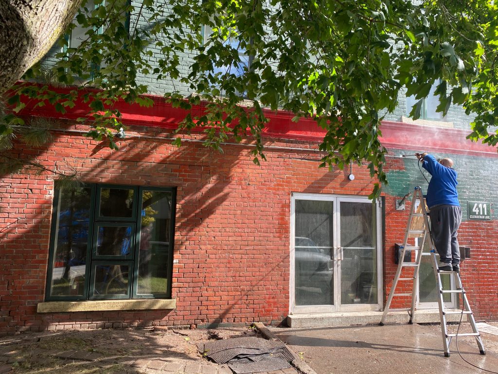 Person power washing the side of the building