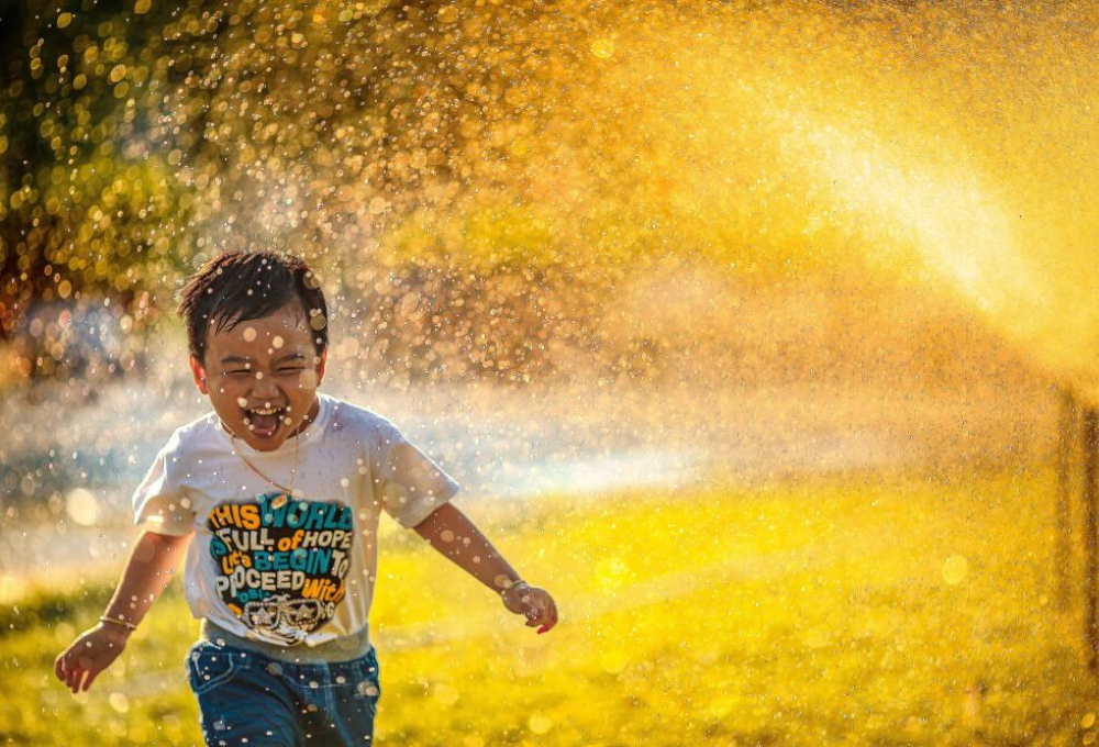 child running through sprinkler