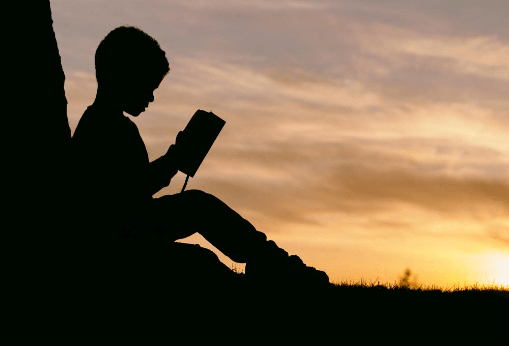 silhouette of child reading 